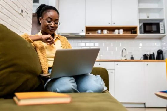 etudiante assise canape dans residence etudiante avec ordinateur